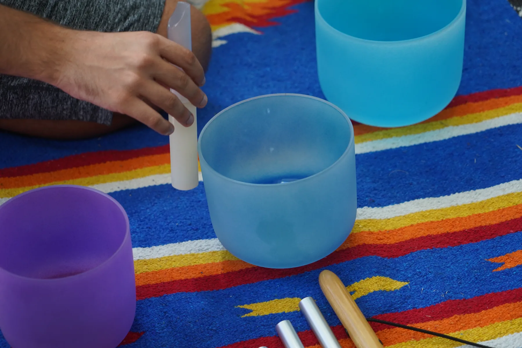 Close-up of a mallet resting against a blue crystal singing bowl