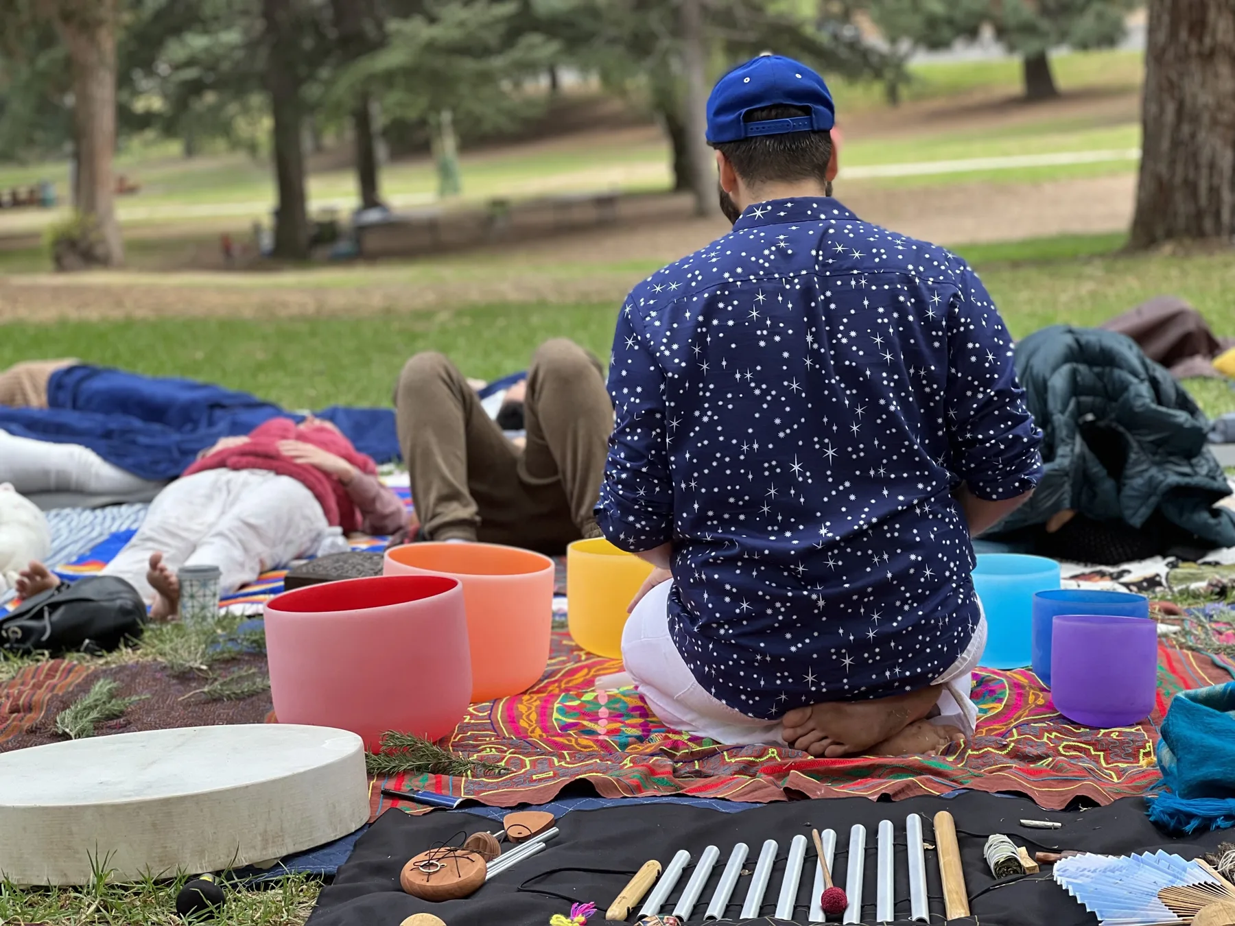 SANTOS surrounded by instruments and listeners at an outdoor sound bath